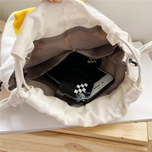Close-up of the spacious interior of a beige canvas drawstring bucket bag with accessories