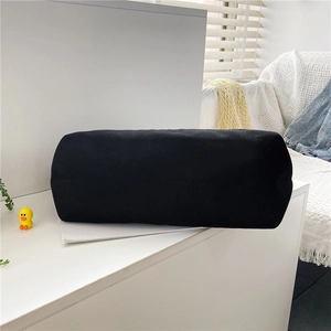 Close-up of black cylindrical canvas storage bag showing durable fabric texture on white table