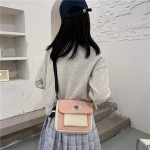 Pink and beige canvas crossbody bag with star embroidery shown on model's back