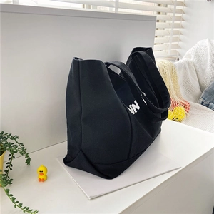 Detail view of a black canvas tote bag with white lettering and sturdy double straps