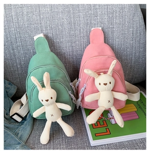Détail de sacs bandoulière en toile rose et vert avec d'adorables poupées lapin en peluche