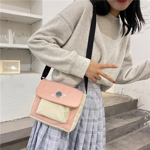 Pink and white canvas crossbody bag with planet graphic worn by a model in casual style