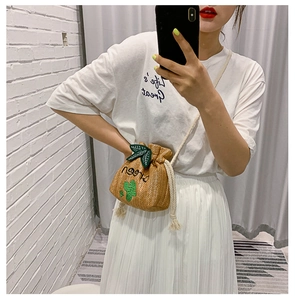 Detailed straw bucket bag featuring green cactus embroidery and white rope drawstrings