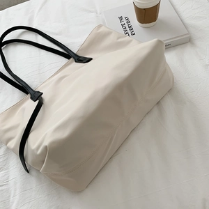 Minimalist large capacity tote bag in cream white with black shoulder straps for daily use