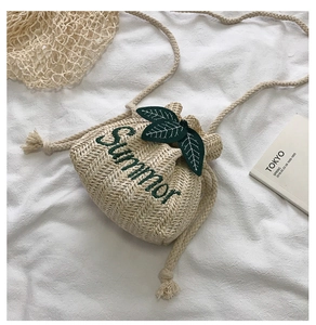 Detail of summer straw bucket bag showing 'Summer' embroidery and decorative green leaves