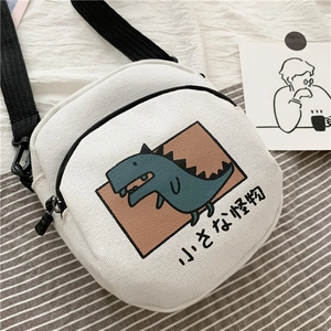 Détail du sac bandoulière en toile blanche avec dinosaure et sangle réglable