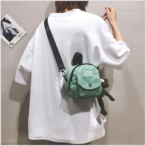 Détail du mini sac bandoulière en toile vert clair avec imprimé CMN et peluche grenouille