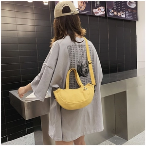 Détail du sac bandoulière en toile jaune en forme de croissant avec broderie minimaliste