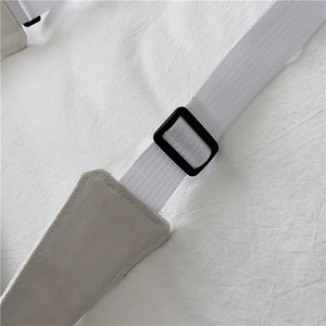 Detail of adjustable white canvas strap with black plastic buckle and premium stitching