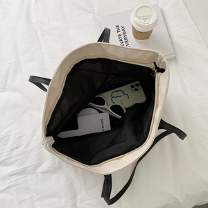 Large capacity off-white tote bag with black handles showing spacious interior storage