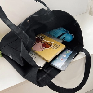 Detail of black canvas tote bag showing large capacity and internal snap button closure