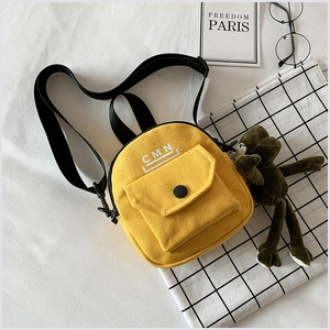 Vue détaillée du sac bandoulière en toile jaune avec imprimé CMN et sangles noires