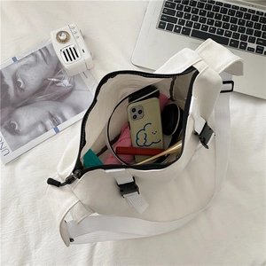 Spacious white canvas messenger bag interior showing phone, headphones, and umbrella