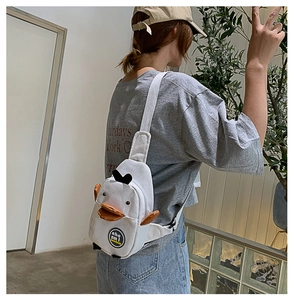 Detailed side view of a white canvas duck-shaped crossbody bag worn by a model