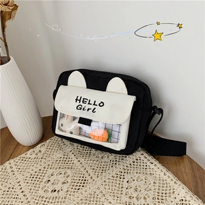 Detail of canvas crossbody bag featuring rabbit ears and clear pocket with plush charms