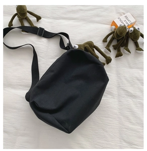 Dettaglio della borsa a tracolla in tela nera con ampia tracolla regolabile in nylon