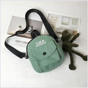 Détail du sac bandoulière en toile vert clair avec sangle réglable et poche avant