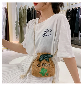 Detail of straw bucket bag featuring green cactus embroidery and leaf drawstring closure