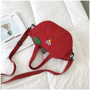 Détail du sac bandoulière en toile rouge avec yeux de dessin animé 3D et sangle