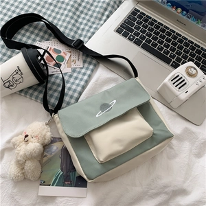 Detail of mint green canvas crossbody bag with planet embroidery and plush bear charm