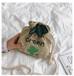 Detail of straw bucket bag with Green embroidery, cactus pattern and drawstring closure