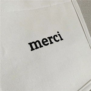 Detail of thick canvas tote bag featuring black merci print and durable stitching