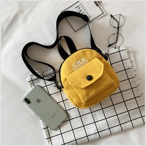 Vue détaillée de dessus d'un mini sac en toile jaune avec imprimé CMN et accessoires