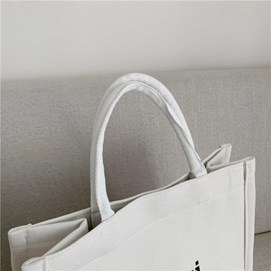 Detail of reinforced handle and precision stitching on the white canvas tote bag