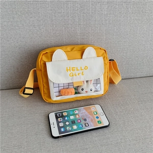 Detail view of the yellow cartoon shoulder bag size compared to a smartphone