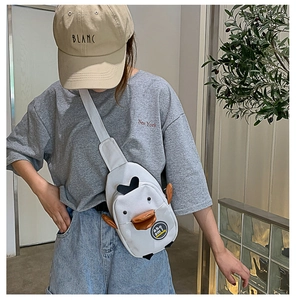 Detail of cute white duck canvas chest bag with adjustable strap worn by a model