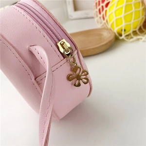 Detailed macro shot of girls' pink donut bag showing flower zipper and leather texture