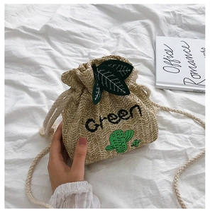 Detail of straw bucket bag featuring green cactus embroidery and cotton rope strap
