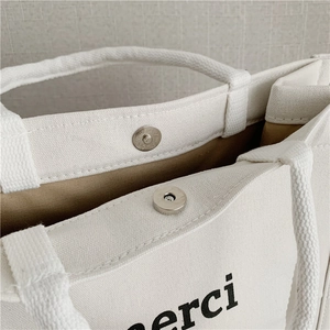 Detail of canvas tote bag with metal magnetic closure and textured rope handles