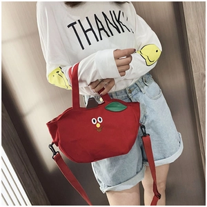 Détail du sac en toile rouge en forme de pomme avec broderie et bandoulière réglable