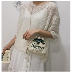 Close-up of beige woven bucket bag with green Summer embroidery and leaf details