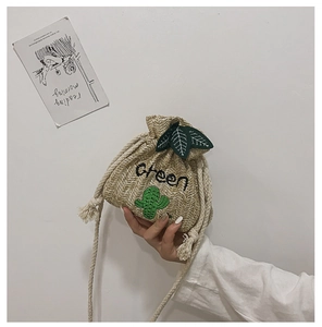 Detail of woven straw bucket bag with green cactus embroidery and drawstring closure