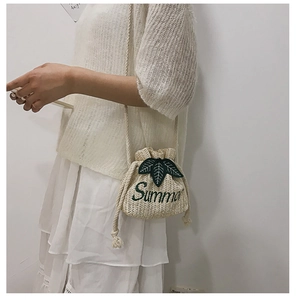 Close-up of beige woven bucket bag featuring green leaf patch and Summer embroidery