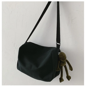 Dettaglio borsa in tela nera con ciondolo a rana in peluche verde e occhi a X
