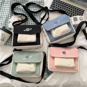 Detail of four colorful canvas crossbody bags with planet embroidery on white background