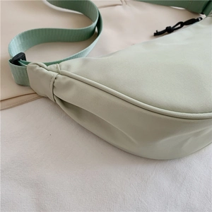 Detail of light green nylon crescent bag showing durable fabric and wide woven strap