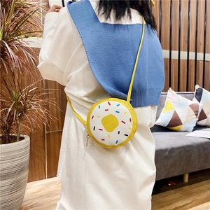 Close-up of a cute yellow donut-shaped crossbody bag worn by a girl in a home setting