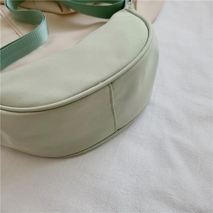 Close-up of mint green nylon dumpling bag showing side seams and wide fabric strap
