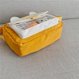 Close-up of yellow canvas bag with rabbit accessories and HELLO text detail