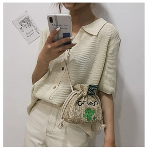 Detail of straw bucket bag with cactus embroidery and green text on woven texture