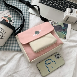 Detail of pink and beige canvas crossbody bag with planet embroidery and adjustable strap