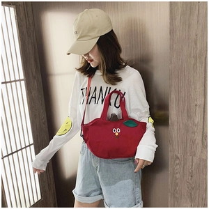 Gros plan d'un sac à bandoulière en toile rouge en forme de pomme avec visage de dessin animé
