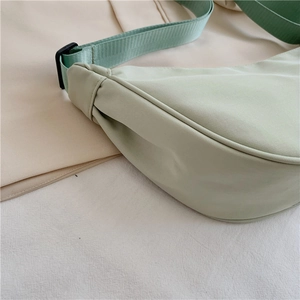 Detailed close-up of light green nylon dumpling bag stitching and smooth fabric texture