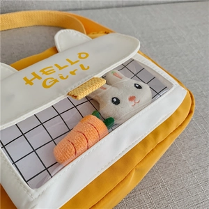 Detail of cute yellow canvas bag featuring transparent PVC window and plush bunny inside