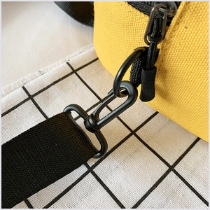 Gros plan du sac en toile jaune avec fermeture éclair noire et boucle de bandoulière