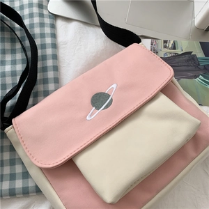 Close-up of a pink and beige canvas crossbody bag featuring a Saturn planet embroidery